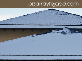Nieve sobre tejados de pizarra sin canalones.